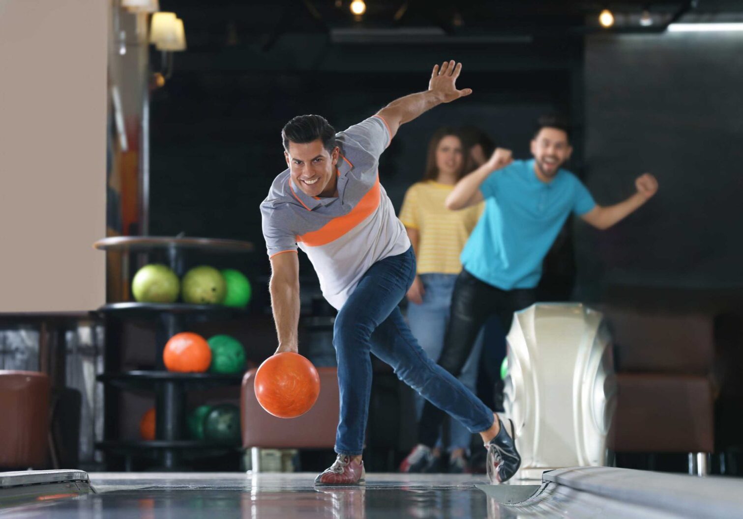 Man throwing ball and spending time with friends in bowling club