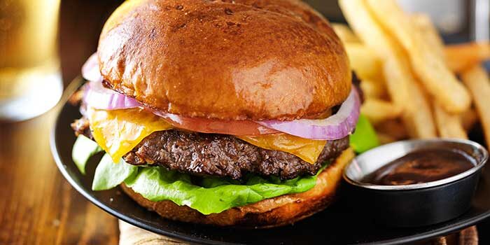 cheeseburger and fries on plate served with beer at restaurant